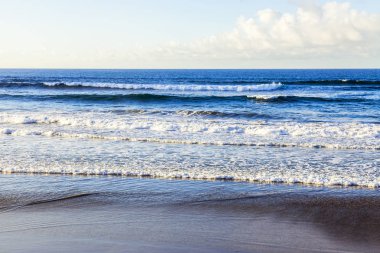 Bir sörf, bulutlu havalarda Atlantik Okyanusu kıyısında pitoresk dalgalar