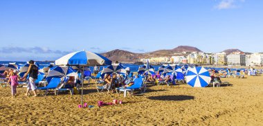 Las Palmas de Gran Canaria, İspanya, 10 Ocak 2018 üzerinde. Kış güneşi Playa de Las Canteras beach Atlantik Okyanusu kıyısında ışıklar. İnsanlar biraz dinlen ve yakın bir su kenarı güneşlenmek
