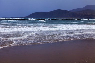 Bir sörf, bulutlu havalarda Atlantik Okyanusu kıyısında pitoresk dalgalar