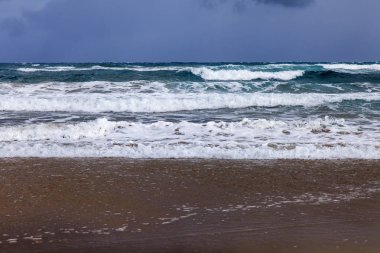 Bir sörf, bulutlu havalarda Atlantik Okyanusu kıyısında pitoresk dalgalar