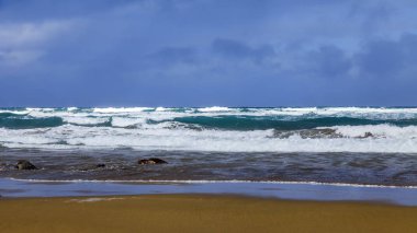 Bir sörf, bulutlu havalarda Atlantik Okyanusu kıyısında pitoresk dalgalar