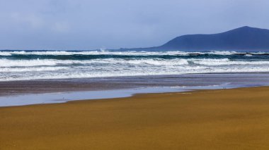Bir sörf, bulutlu havalarda Atlantik Okyanusu kıyısında pitoresk dalgalar