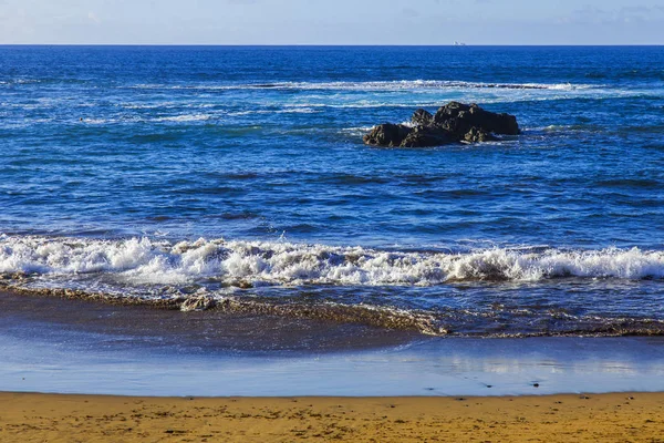 Bir sörf, bulutlu havalarda Atlantik Okyanusu kıyısında pitoresk dalgalar