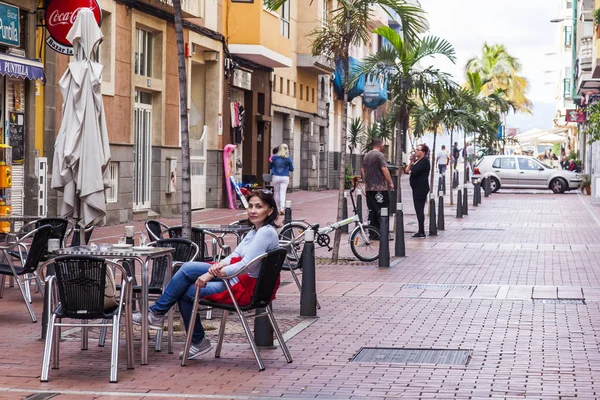 Las Palmas de Gran Canaria, İspanya, 10 Ocak 2018 üzerinde. Modern binalar mimari kompleks sokağın adalar adalar için tipik olun. Kadın sokak kafe küçük bir masada oturur