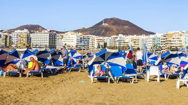 Las Palmas de Gran Canaria, İspanya, 10 Ocak 2018 üzerinde. Kış güneşi Playa de Las Canteras beach Atlantik Okyanusu kıyısında ışıklar. İnsanlar biraz dinlen ve yakın bir su kenarı güneşlenmek