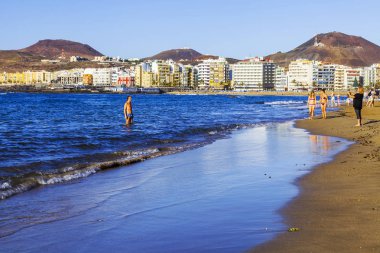 Las Palmas de Gran Canaria, İspanya, 10 Ocak 2018 üzerinde. Kış güneşi Playa de Las Canteras beach Atlantik Okyanusu kıyısında ışıklar. İnsanlar biraz dinlen ve yakın bir su kenarı güneşlenmek
