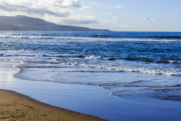 Picturesque surf at the coast of the Atlantic Ocean in cloudy weather