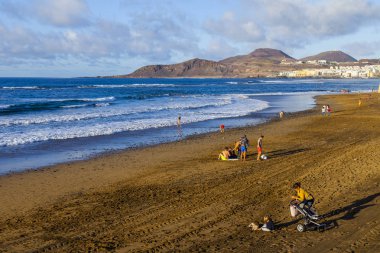 Las Palmas de Gran Canaria, İspanya, 10 Ocak 2018 üzerinde. Kış güneşi Playa de Las Canteras beach Atlantik Okyanusu kıyısında ışıklar. İnsanlar biraz dinlen ve bir su kenarı güneşlenmek