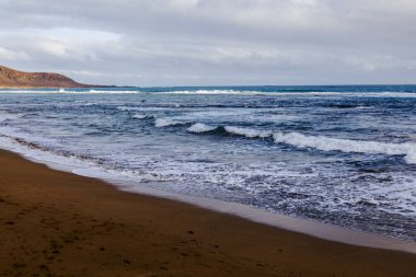 Bulutlu havalarda Atlantik Okyanusu kıyısında, pitoresk sörf