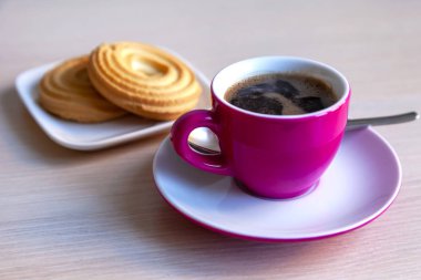 Espresso kahve parlak pembe porselen fincan ve bir tabak kurabiye