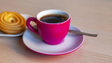 Espresso kahve parlak pembe porselen fincan ve bir tabak kurabiye