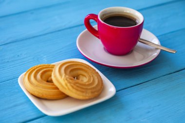 Espresso kahve parlak pembe porselen fincan ve bir tabak kurabiye