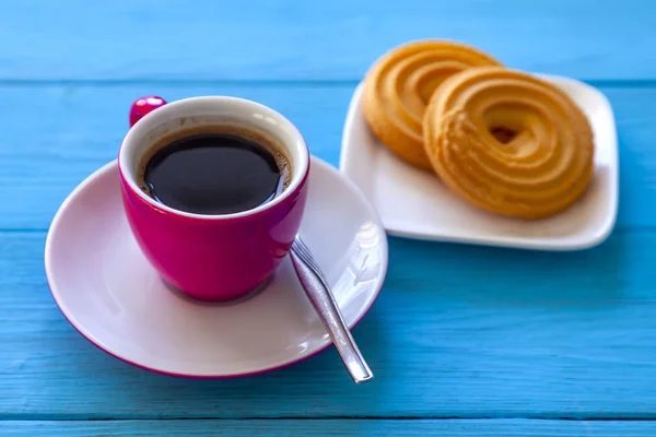 Espresso coffee in a bright pink porcelain cup and cookies on a saucer