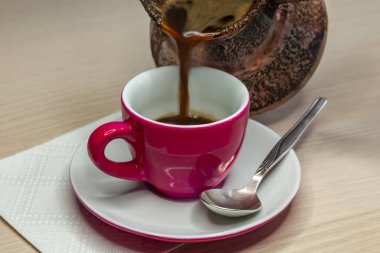 Siyah kahve cezve parlak pembe kahve Kupası'nda üzerinden akar