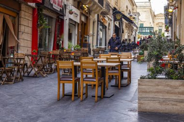 Valletta, Malta, üzerinde 8 Ocak 2019. İnsanlar eski şehrin yoğun alışveriş caddesi boyunca gidin. Masalara sokak Cafe ziyaretçiler için