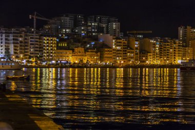 Sliema, Malta, 5 Ocak 2019 tarihinde. Gece bak. defne suya yansıyan akşam yangınlar ile Bay pitoresk setin yaktı
