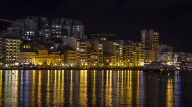Sliema, Malta, 5 Ocak 2019 tarihinde. Gece bak. defne suya yansıyan akşam yangınlar ile Bay pitoresk setin yaktı