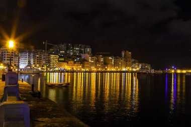 Sliema, Malta, 5 Ocak 2019 tarihinde. Gece bak. defne suya yansıyan akşam yangınlar ile Bay pitoresk setin yaktı