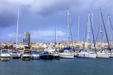 Il-Gzira, Malta, üzerinde 8 Ocak 2019. Yürüyen tekneler ve yatlar pitoresk koyda demirlemiş. Bulutlu hava