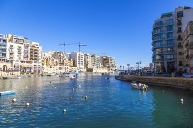 San Giljan, Malta, üzerinde 8 Ocak 2019. Pitoresk koyda yürüyen tekneler güneşin ile kış sabahları yanıyor. Uzaktan güzel dolgu