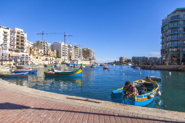 San Giljan, Malta, üzerinde 8 Ocak 2019. Pitoresk koyda yürüyen tekneler güneşin ile kış sabahları yanıyor. Uzaktan güzel dolgu