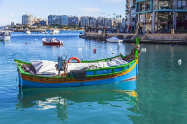 San Giljan, Malta, üzerinde 8 Ocak 2019. Pitoresk koyda yürüyen tekneler güneşin ile kış sabahları yanıyor. Uzaktan güzel dolgu