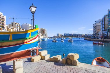 San Giljan, Malta, üzerinde 8 Ocak 2019. Pitoresk koyda yürüyen tekneler güneşin ile kış sabahları yanıyor. Uzaktan güzel dolgu