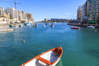 San Giljan, Malta, üzerinde 8 Ocak 2019. Pitoresk koyda yürüyen tekneler güneşin ile kış sabahları yanıyor. Uzaktan güzel dolgu