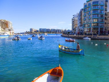 San Giljan, Malta, üzerinde 8 Ocak 2019. Pitoresk koyda yürüyen tekneler güneşin ile kış sabahları yanıyor. Uzaktan güzel dolgu