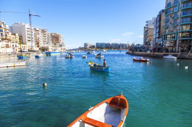 San Giljan, Malta, üzerinde 8 Ocak 2019. Pitoresk koyda yürüyen tekneler güneşin ile kış sabahları yanıyor. Uzaktan güzel dolgu