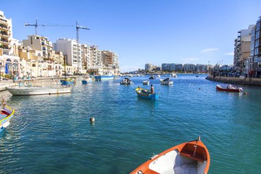 San Giljan, Malta, 7 Ocak 2019 tarihinde. Yürüyüş ve balıkçı tekneleri pitoresk defne Spinola içinde güneşin ile kış sabahları yanıyor. Uzaktan güzel dolgu