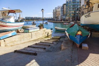 San Giljan, Malta, 7 Ocak 2019 tarihinde. Spinola Körfezi'nin güzel dolgu. Yürüyüş ve balıkçı tekneleri defne Spinola kıyısında güneşli kış günü
