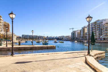 San Giljan, Malta, 7 Ocak 2019 tarihinde. Yürüyüş ve balıkçı tekneleri pitoresk defne Spinola içinde güneşin ile kış sabahları yanıyor. Uzaktan güzel dolgu