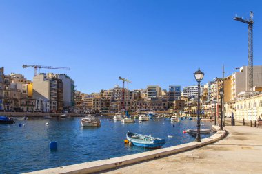 San Giljan, Malta, 7 Ocak 2019 tarihinde. Yürüyüş ve balıkçı tekneleri pitoresk defne Spinola içinde güneşin ile kış sabahları yanıyor. Uzaktan güzel dolgu