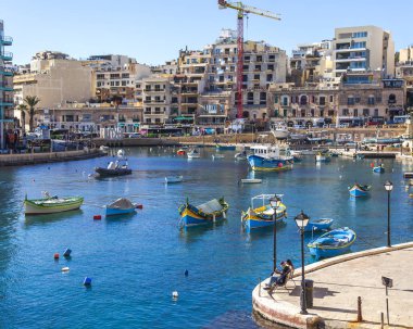 San Giljan, Malta, 7 Ocak 2019 tarihinde. Yürüyüş ve balıkçı tekneleri pitoresk defne Spinola içinde güneşin ile kış sabahları yanıyor. Uzaktan güzel dolgu