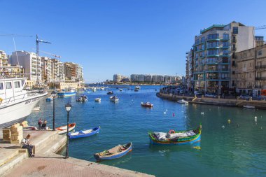 San Giljan, Malta, 7 Ocak 2019 tarihinde. Yürüyüş ve balıkçı tekneleri pitoresk defne Spinola içinde güneşin ile kış sabahları yanıyor. Uzaktan güzel dolgu