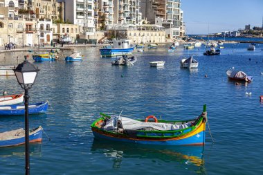San Giljan, Malta, 7 Ocak 2019 tarihinde. Yürüyüş ve balıkçı tekneleri pitoresk defne Spinola içinde güneşin ile kış sabahları yanıyor. Uzaktan güzel dolgu