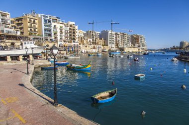San Giljan, Malta, 7 Ocak 2019 tarihinde. Yürüyüş ve balıkçı tekneleri pitoresk defne Spinola içinde güneşin ile kış sabahları yanıyor. Uzaktan güzel dolgu
