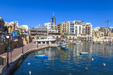 San Giljan, Malta, 7 Ocak 2019 tarihinde. Yürüyüş ve balıkçı tekneleri pitoresk defne Spinola içinde güneşin ile kış sabahları yanıyor. Uzaktan güzel dolgu