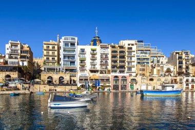 San Giljan, Malta, 7 Ocak 2019 tarihinde. Yürüyüş ve balıkçı tekneleri pitoresk defne Spinola içinde güneşin ile kış sabahları yanıyor. Uzaktan güzel dolgu