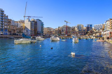 San Giljan, Malta, 7 Ocak 2019 tarihinde. Yürüyüş ve balıkçı tekneleri pitoresk defne Spinola içinde güneşin ile kış sabahları yanıyor. Uzaktan güzel dolgu