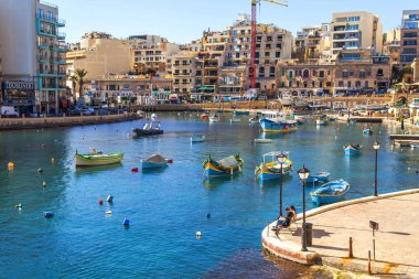 San Giljan, Malta, 7 Ocak 2019 tarihinde. Yürüyüş ve balıkçı tekneleri pitoresk defne Spinola içinde güneşin ile kış sabahları yanıyor. Uzaktan güzel dolgu