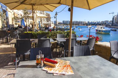 San Giljan, Malta, üzerinde 8 Ocak 2019. Tablolar setin Spinola Körfezi üzerinde pitoresk sokak Cafe