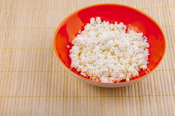 Fresh cottage cheese in a red bowl on a table