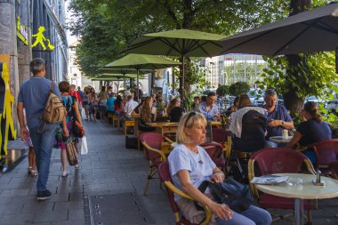 Münih, Almanya, on 16 Ağustos 2018. İnsanlar Bavyera'nın başkentinin eski şehrindeki sokak kafesinin masalarında yemek yiyip dinleniyor. 