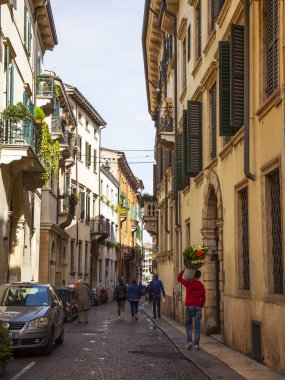 Verona, İtalya, 24 Nisan 2019 tarihinde. İnsanlar eski şehirde dar pitoresk sokak boyunca gitmek