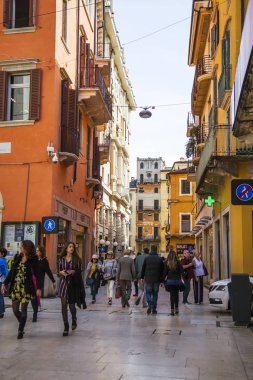 Verona, İtalya, 24 Nisan 2019 tarihinde. İnsanlar eski şehirde dar pitoresk sokak boyunca gitmek