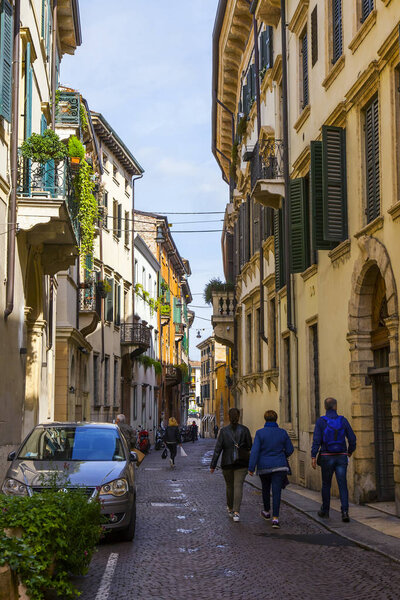 Verona, Italy, on April 24, 2019. People go along the narrow picturesque street in the old city