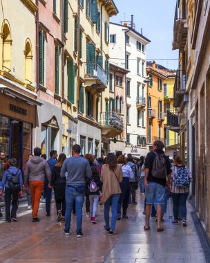 Verona, İtalya, 24 Nisan 2019 tarihinde. İnsanlar eski şehirde tipik bir mimari kompleksi ile dar pitoresk sokak boyunca gitmek
