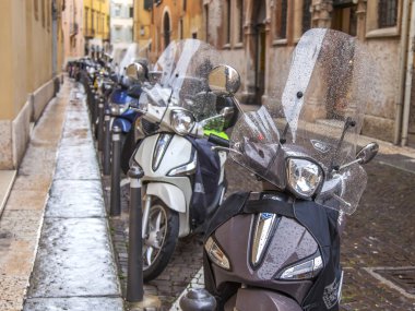 Verona, İtalya, 24 Nisan 2019 tarihinde. eski şehirde tipik bir mimari kompleksi ile güzel sokak. Motosikletler ve scooterlar kaldırıma park edilmiş.